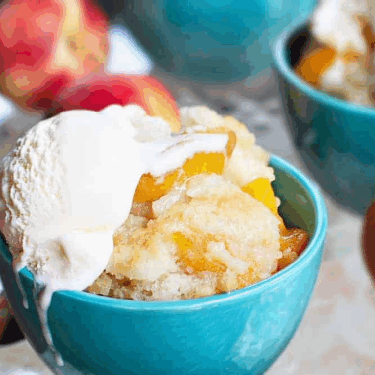 Warm Longhorn Steakhouse Grilled Peach Cobbler copycat served in a cast iron dish, topped with a scoop of melting vanilla ice cream.