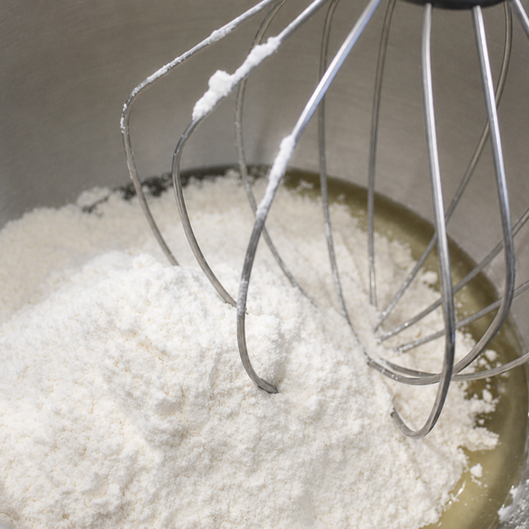 Sugar, oil, milk, vanilla, and eggs whisked smooth in a large glass mixing bowl