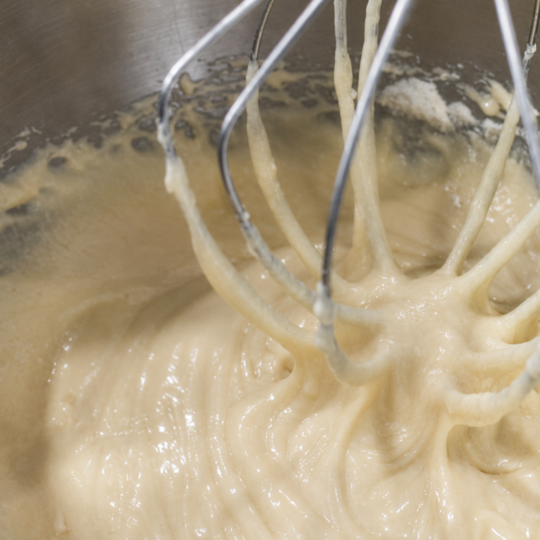 Flour, baking powder, and salt mixed into cranberry bread batter with a spatula