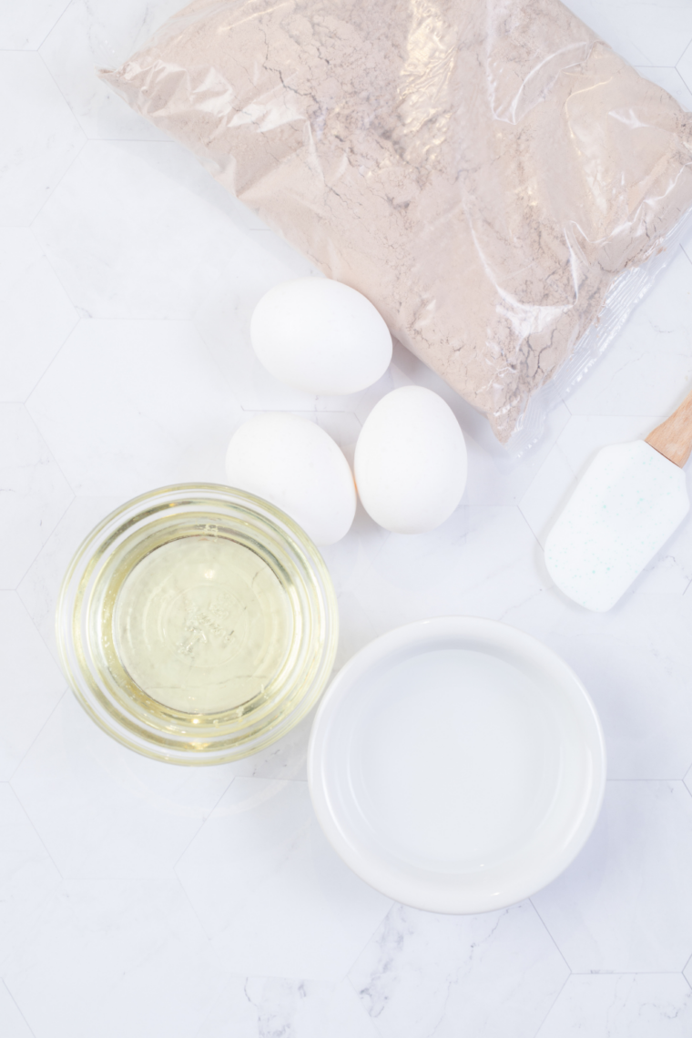 Mixing boxed cake mix with eggs, oil, and water in a bowl until just combined for baking