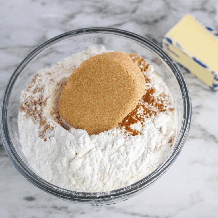 Mixing flour, brown sugar, baking powder, nutmeg, salt, butter, cream, and egg to form scone dough in a bowl