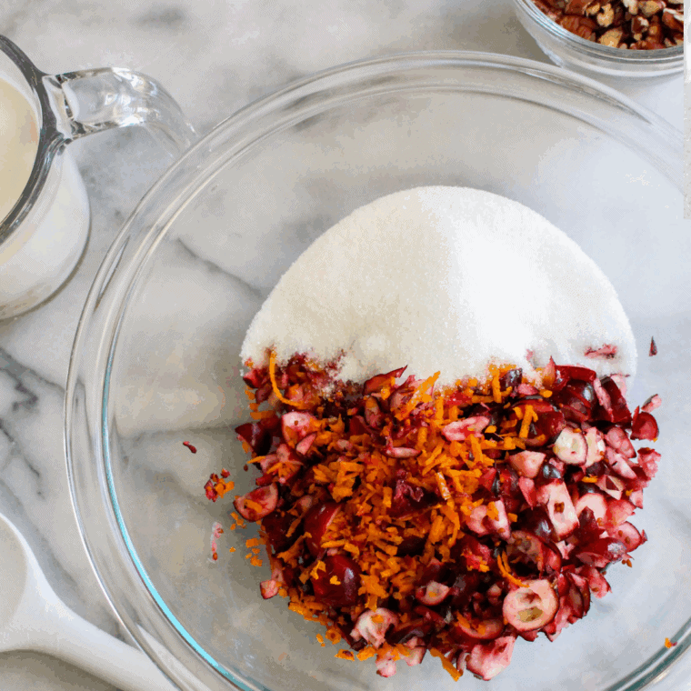 Mixing cranberries, sugar, and orange zest into scone dough on floured surface.
