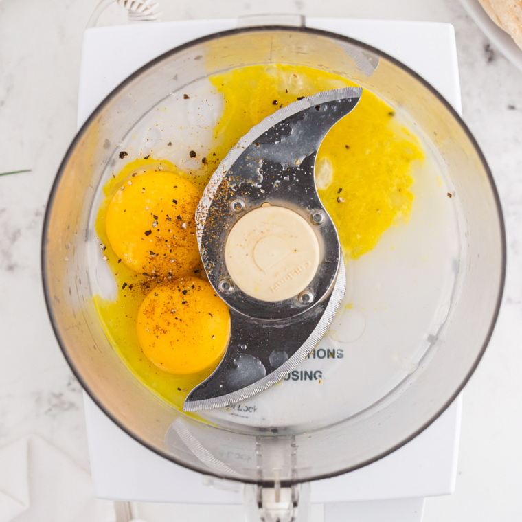 Blender mixing egg yolks lemon juice cayenne salt until pale frothy hollandaise sauce forming while hot butter drizzles slowly to emulsify and thicken