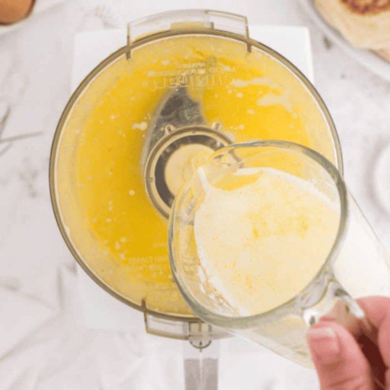 Making blender hollandaise sauce with egg yolks lemon juice cayenne blending while slowly adding hot melted butter until smooth thick creamy consistency achieved