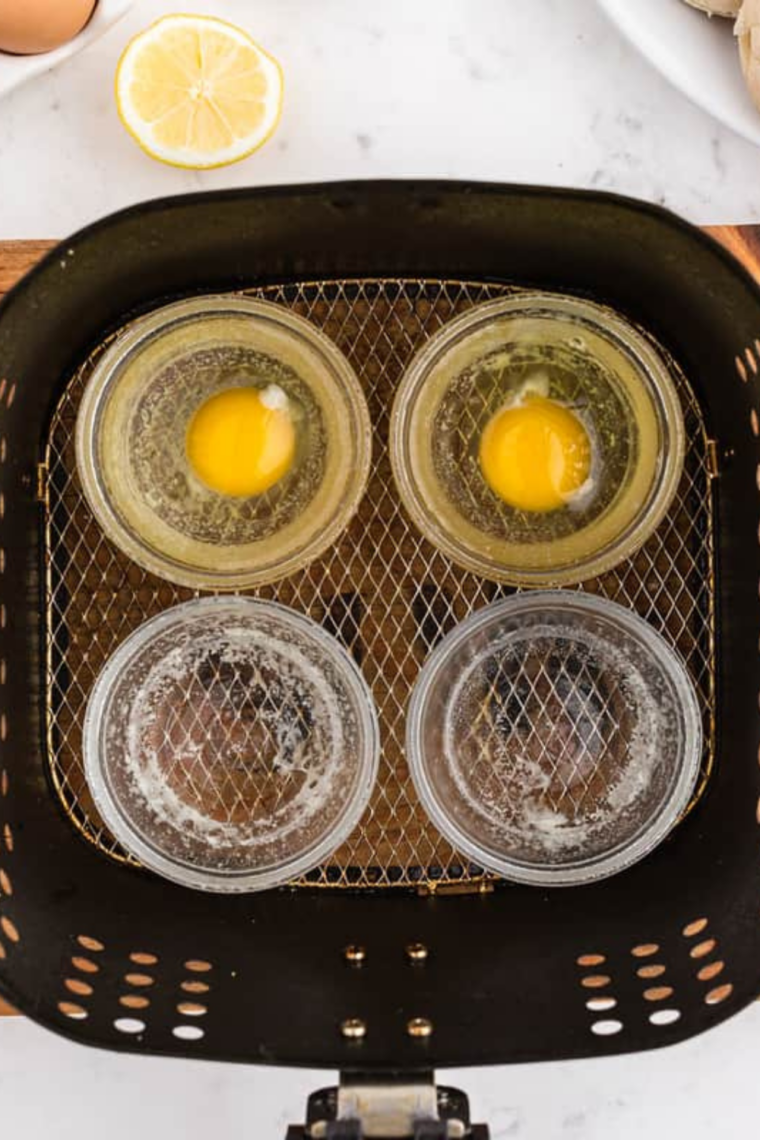Toasted English muffins and heated Canadian bacon in air fryer basket.
