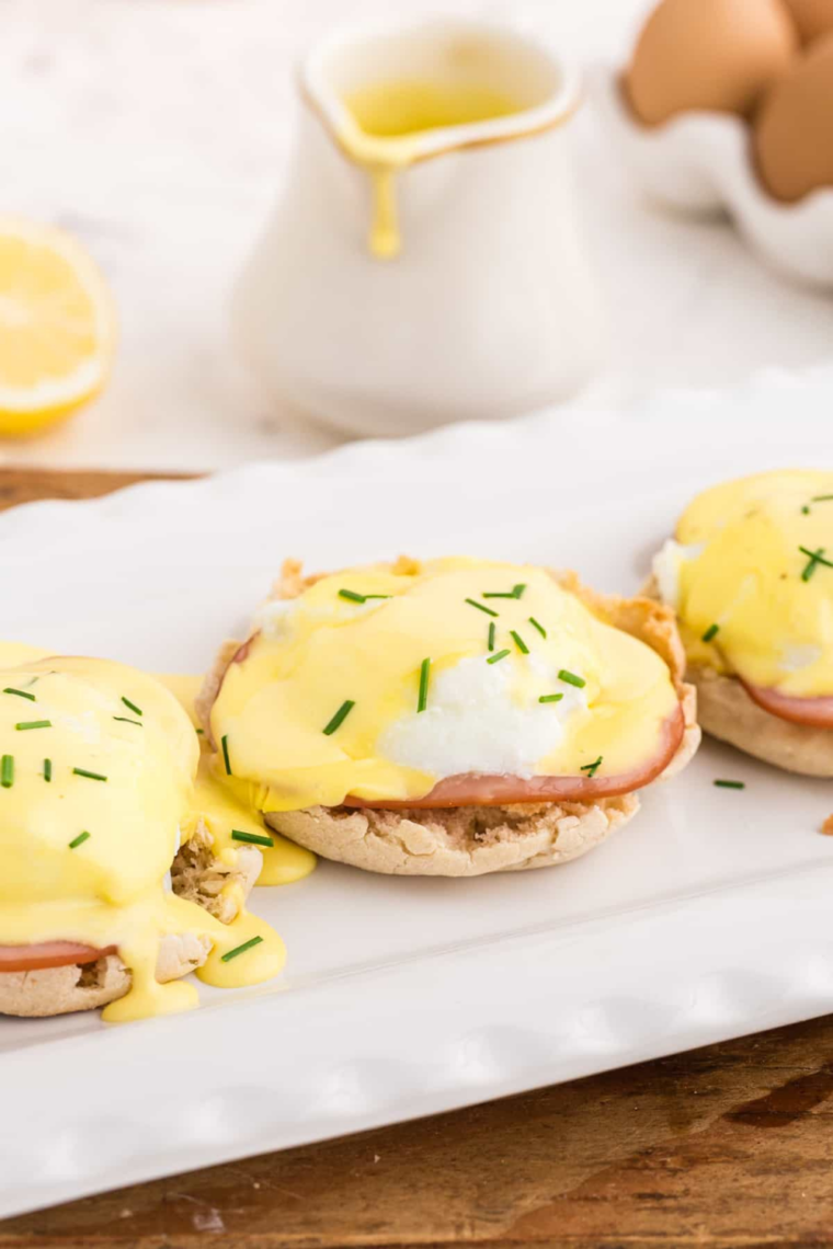 Air Fryer Eggs Benedict with toasted English muffins, Canadian bacon, poached eggs, and drizzled hollandaise garnished with chopped chives