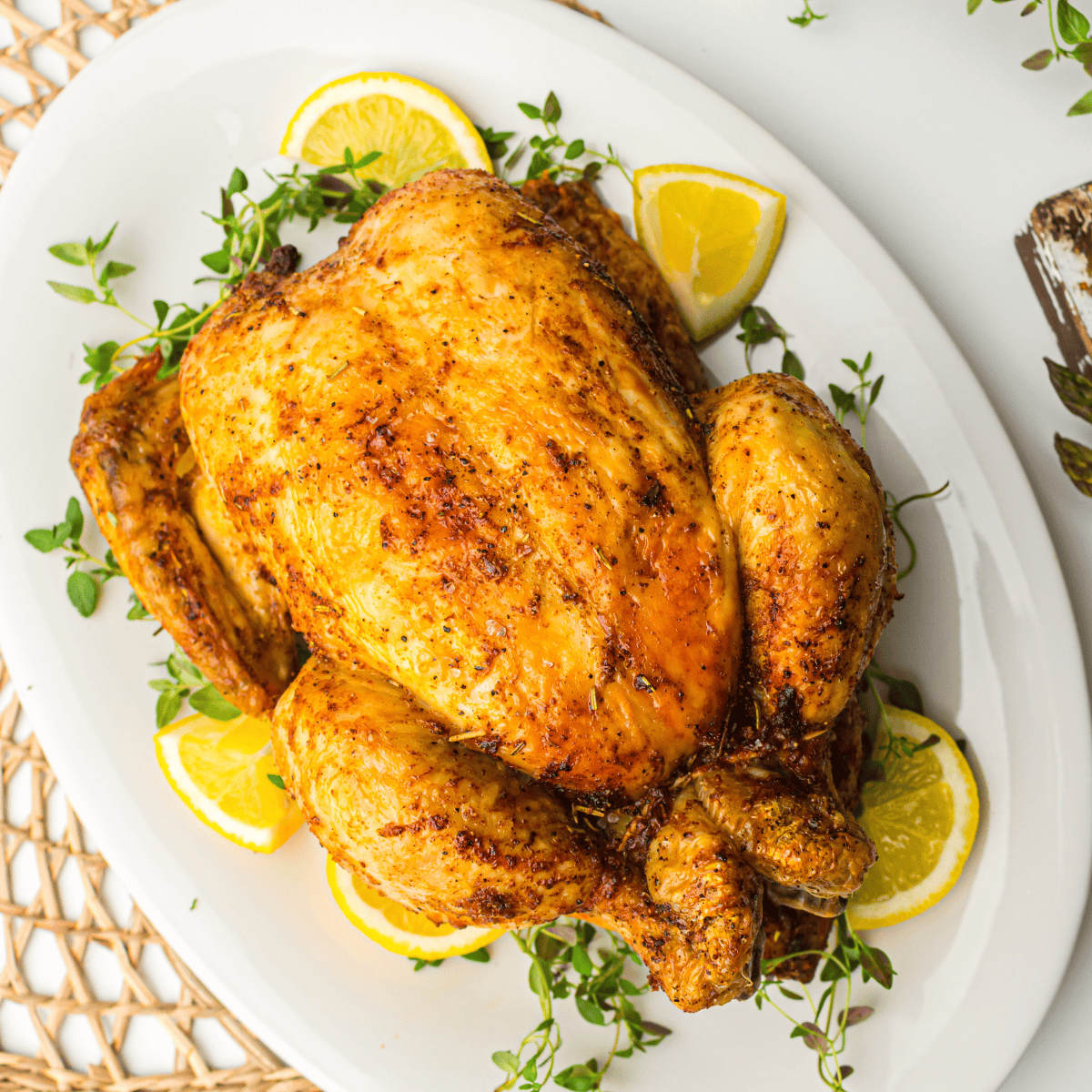 Golden-brown roasted Amish whole chicken on a serving platter, garnished with fresh herbs.