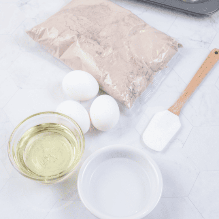 Boxed brownie mix, eggs, oil, and water laid out for air fryer brownies