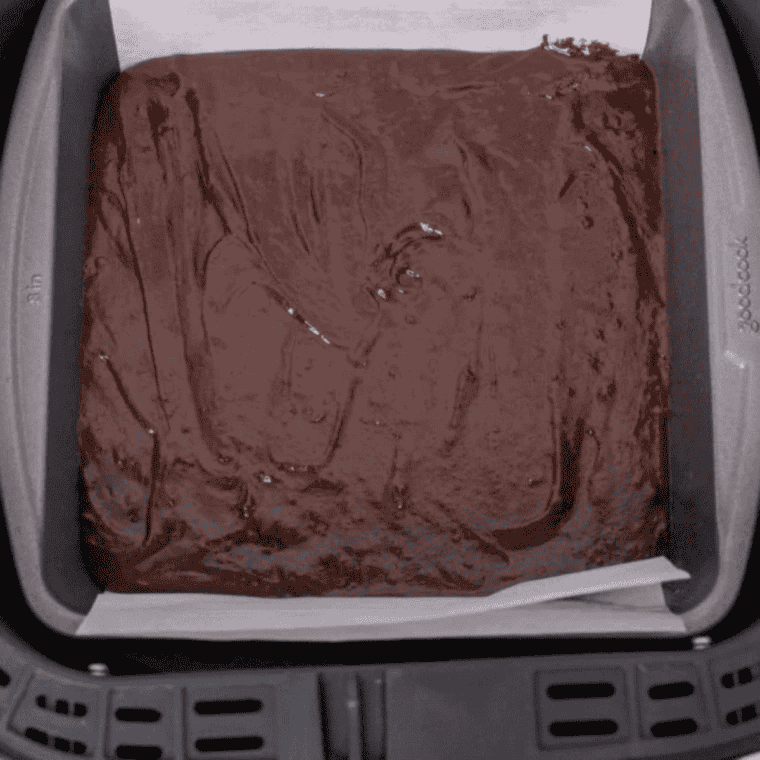 Air fryer boxed brownie batter spread evenly in a parchment-lined pan