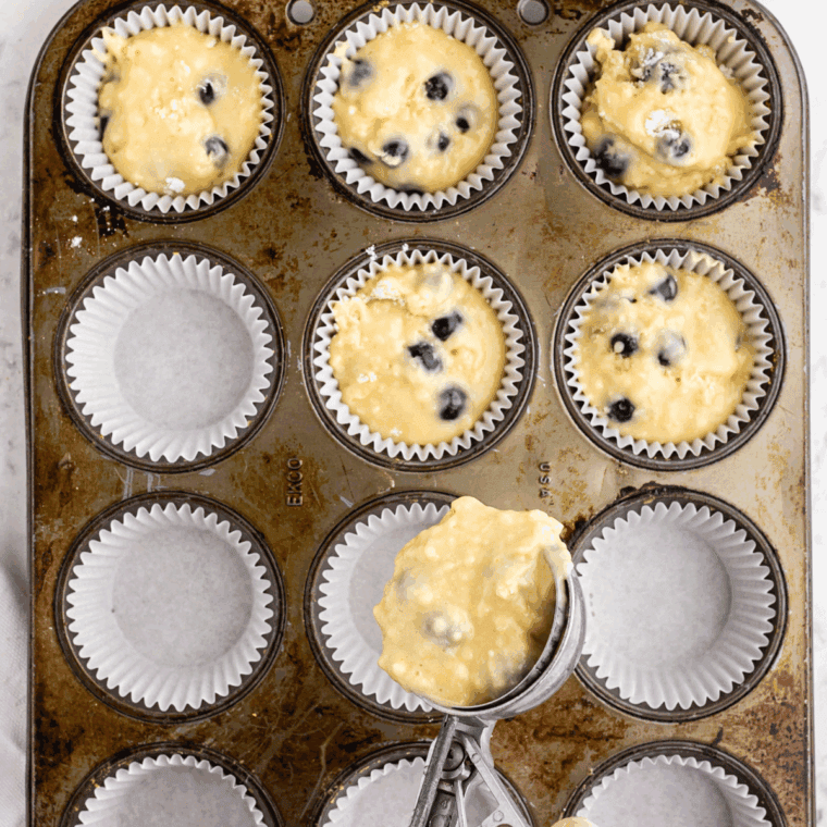 Dividing batter evenly into prepared muffin cups, 2/3 full.