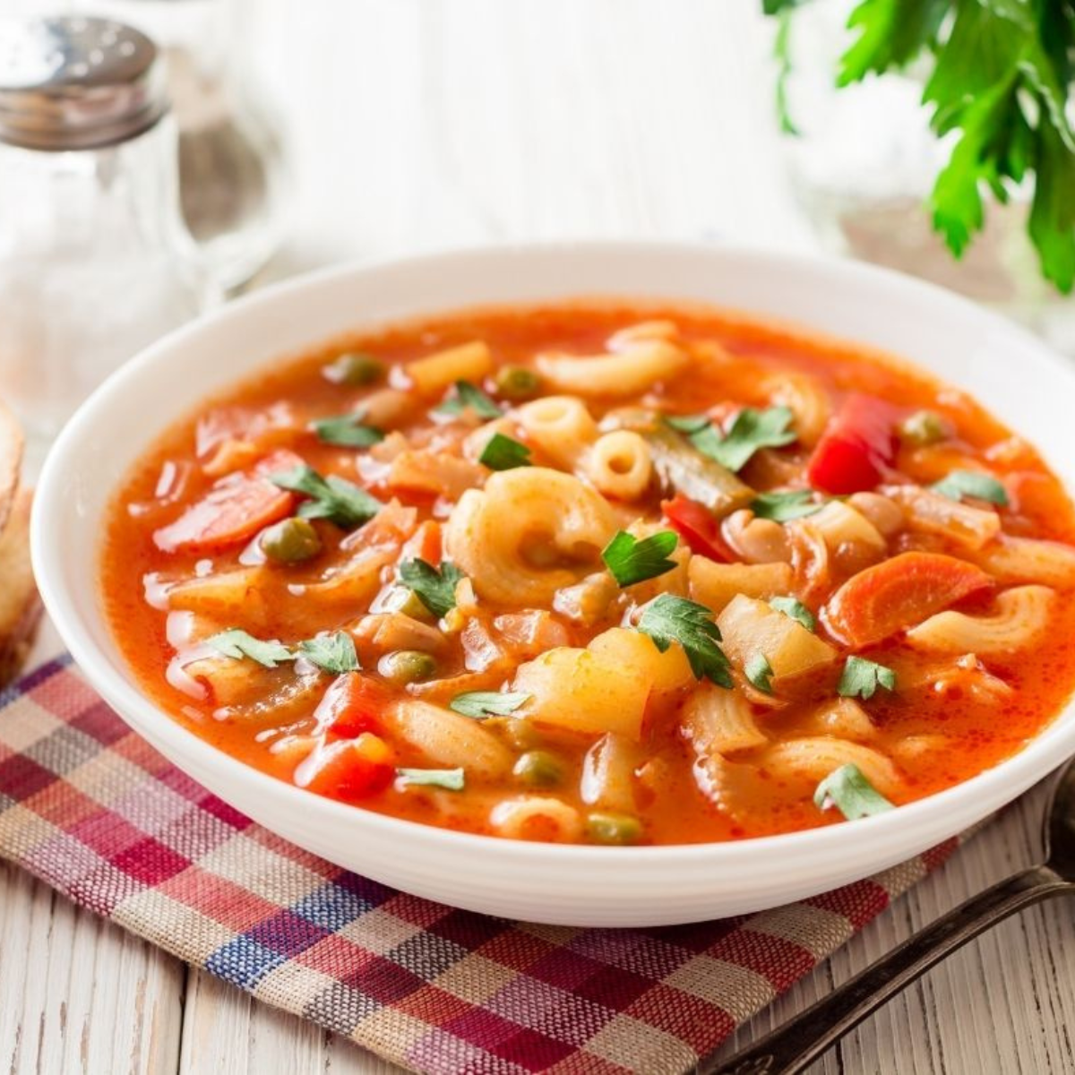 Bowl of minestrone soup topped with pasta, Parmesan, basil, and olive oil drizzle