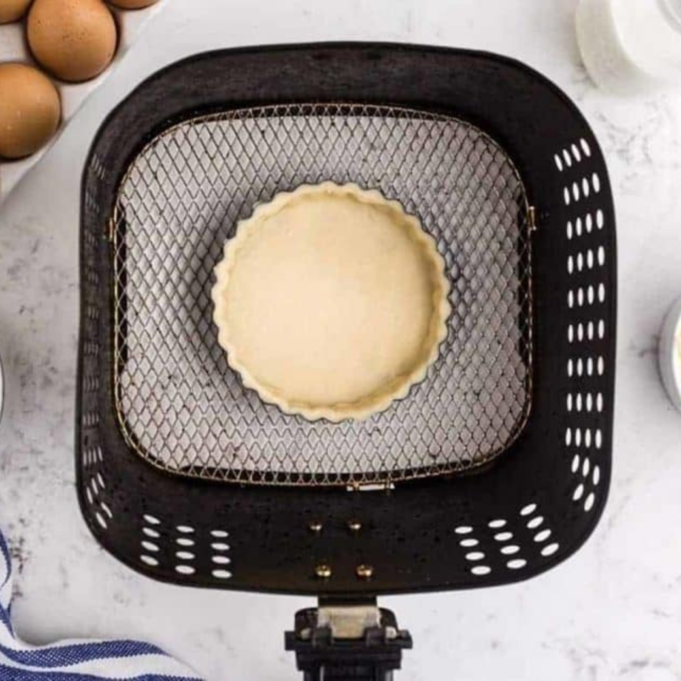 tart pan with pie crust in air fryer basket