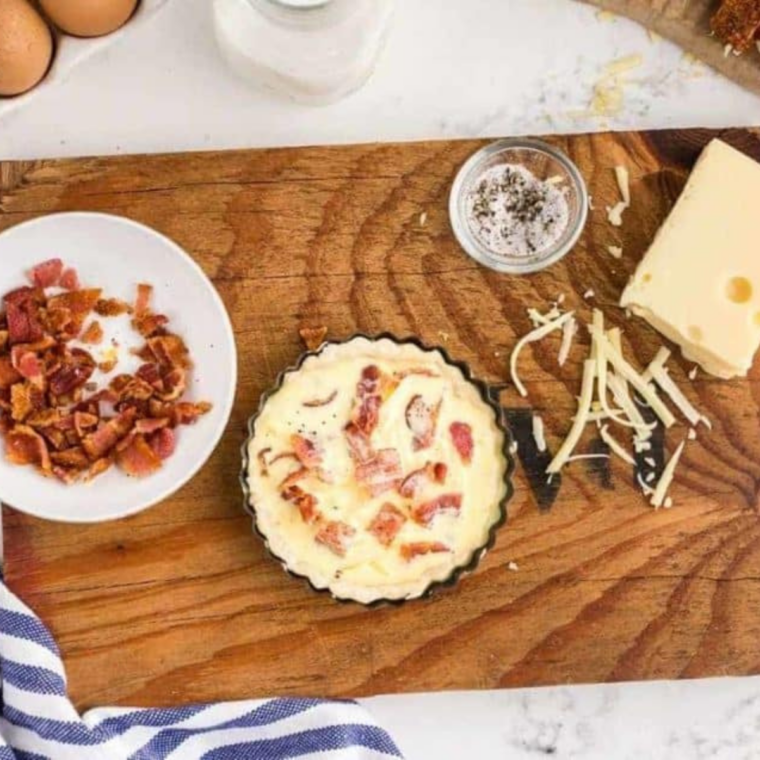 assembled bacon and egg quiche surrounded by ingredients