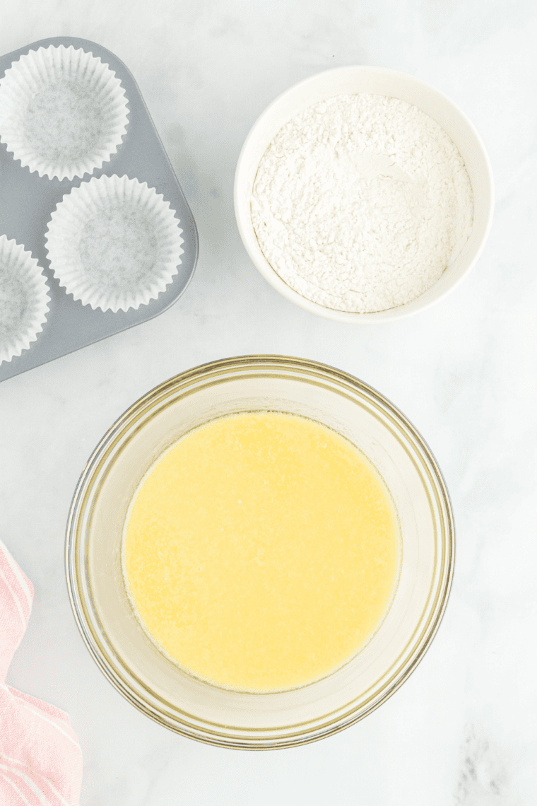 Mixing butter and sugar until fluffy, then adding eggs, vanilla, flour, baking powder, salt, and milk to make smooth cupcake batter.
