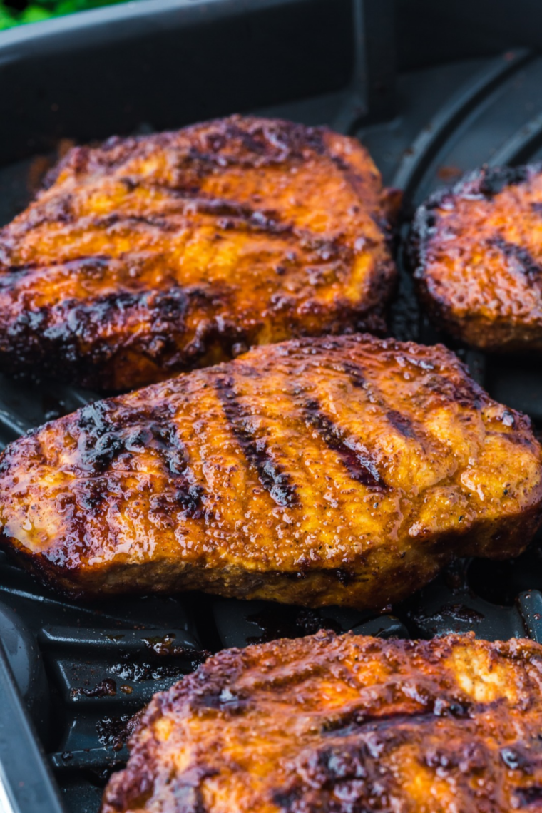 Air fryer blackened pork chops resting on a cutting board with lime wedges before slicing
