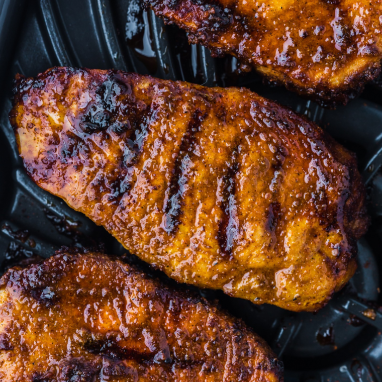 Close-up of blackened pork chops in the air fryer basket with a dark, crispy Cajun spice crust