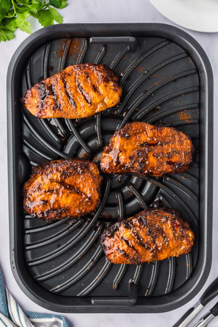 Finished air fryer blackened pork chops in the basket with charred spice crust and visible juices