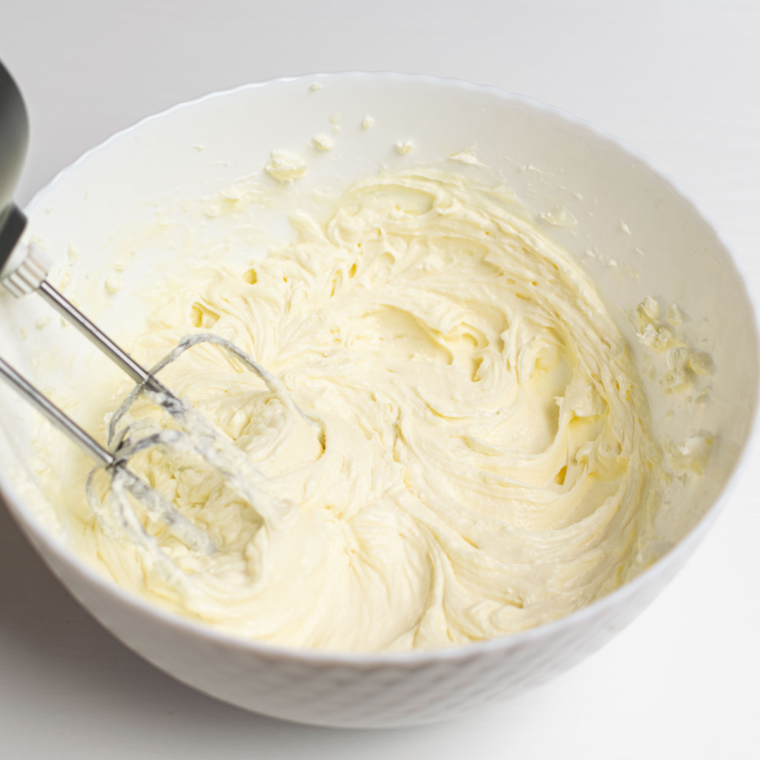 Beating cream cheese and sugar until smooth for vanilla cheesecake filling