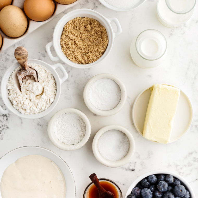 Flour, sugar, eggs, milk, butter, blueberries and cinnamon laid out for blueberry streusel muffins