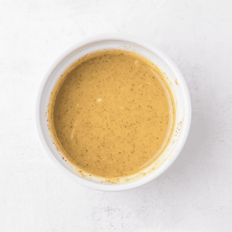 Honey mustard glaze being whisked together in a small bowl.