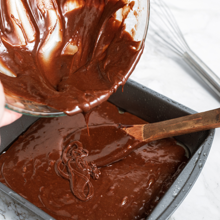 Brownie batter spread in a lined pan and topped with scattered chocolate chunks