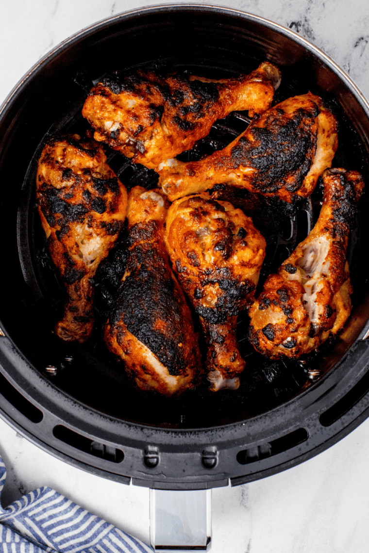 Finished crispy buffalo chicken drumsticks tossed in sauce, ready to serve.
