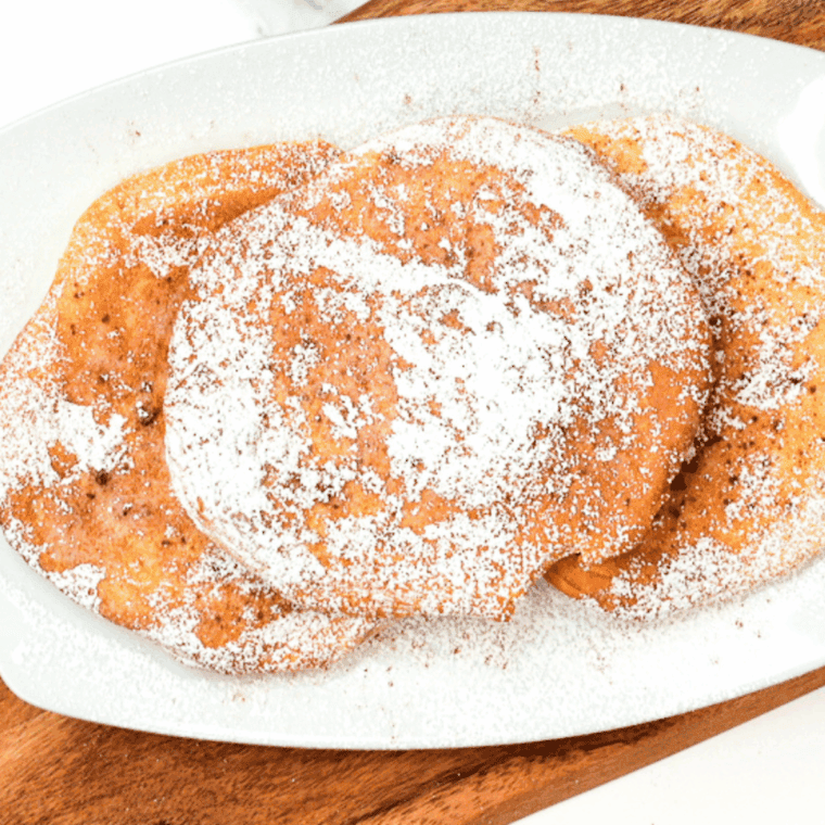 Brushing melted butter onto warm air-fried dough before dipping in cinnamon sugar.