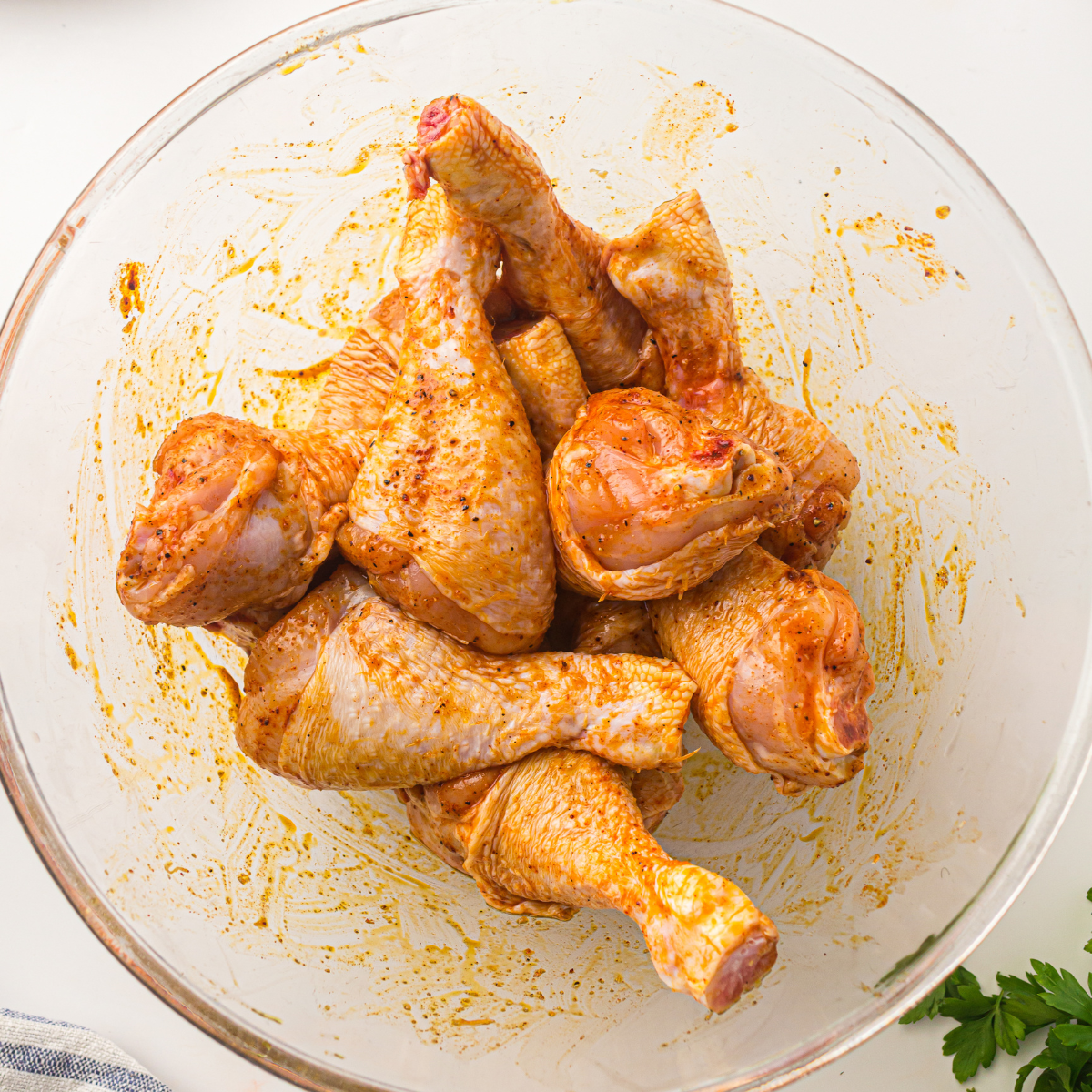 Chicken drumstick being rolled in garlic paprika oil