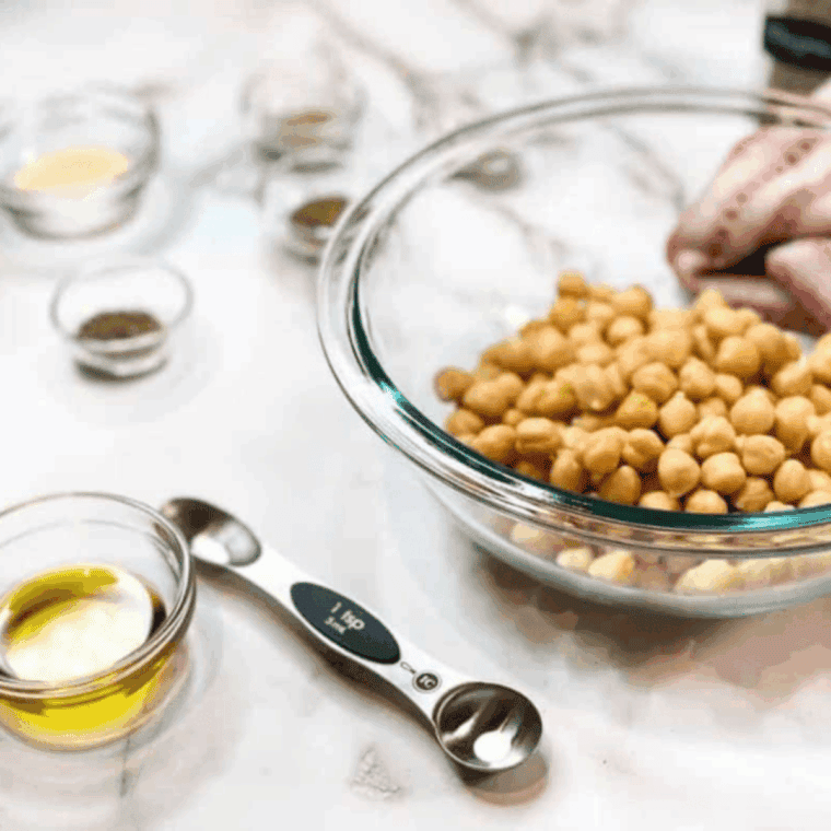 Chickpeas being patted dry with a paper towel after draining and rinsing to prepare for crispy roasting.