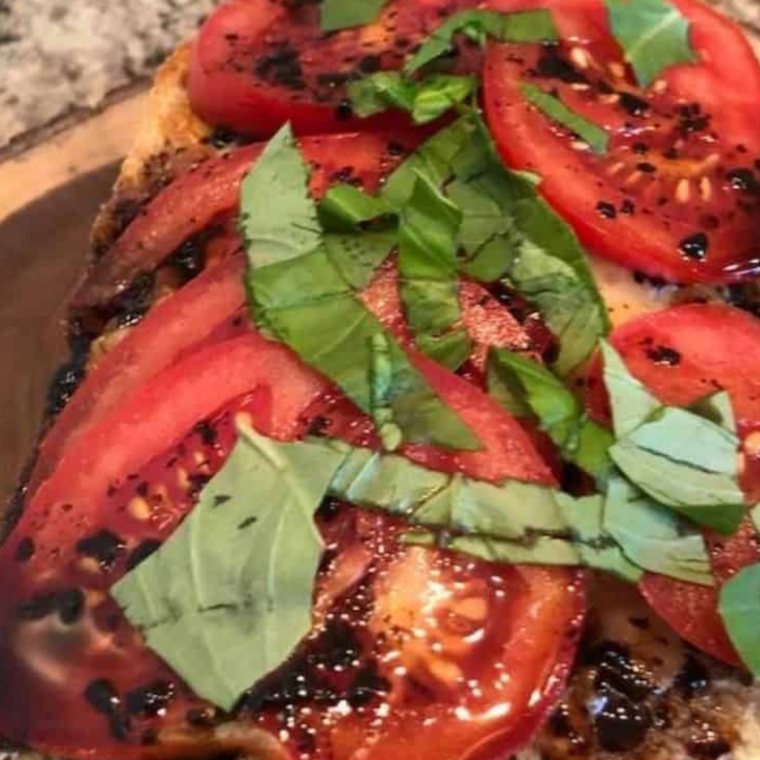 Thin tomato slices layered over melted mozzarella and seasoned with salt and pepper