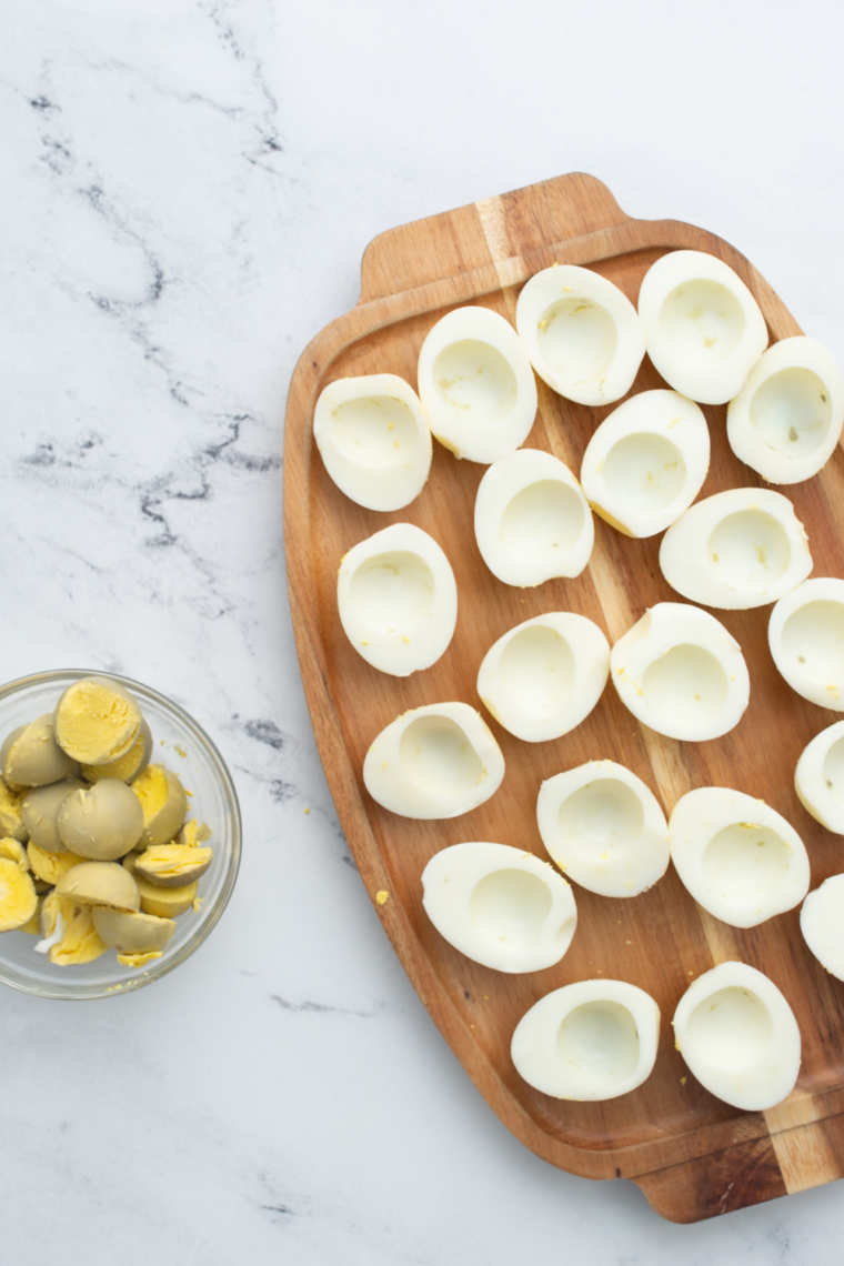 Hands peeling the cracked shell off a hard-boiled egg under cold running water for clean, easy removal.