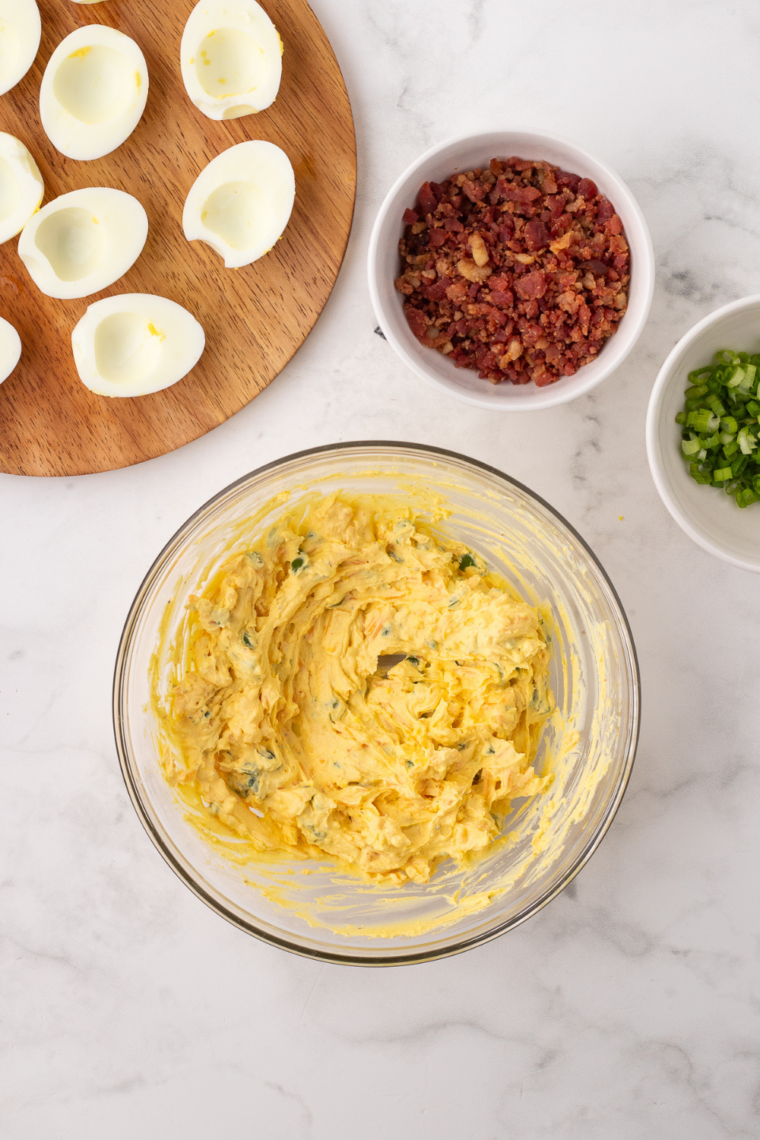 Hard-boiled eggs sliced in half lengthwise with yolks removed, whites arranged on a white serving plate.