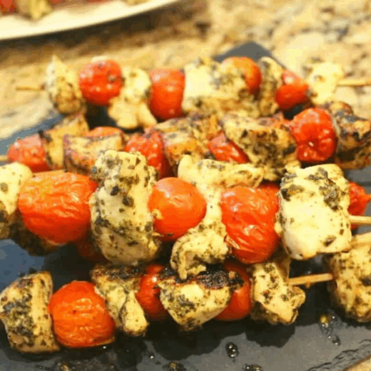 Air Fryer Pesto Chicken and Tomato Kebabs on skewers with fresh basil and cherry tomatoes.