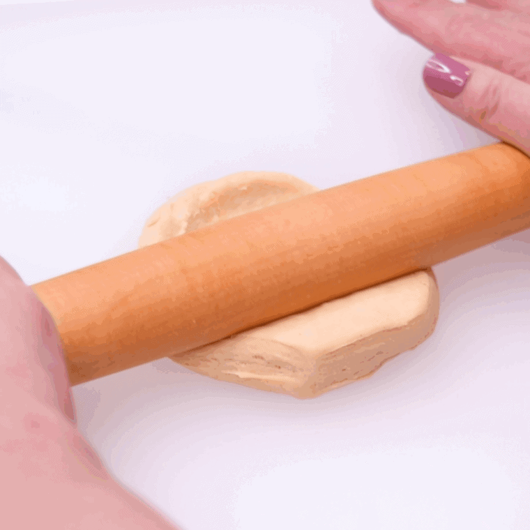 zeppole dough balls arranged in a single layer inside a greased air fryer basket.