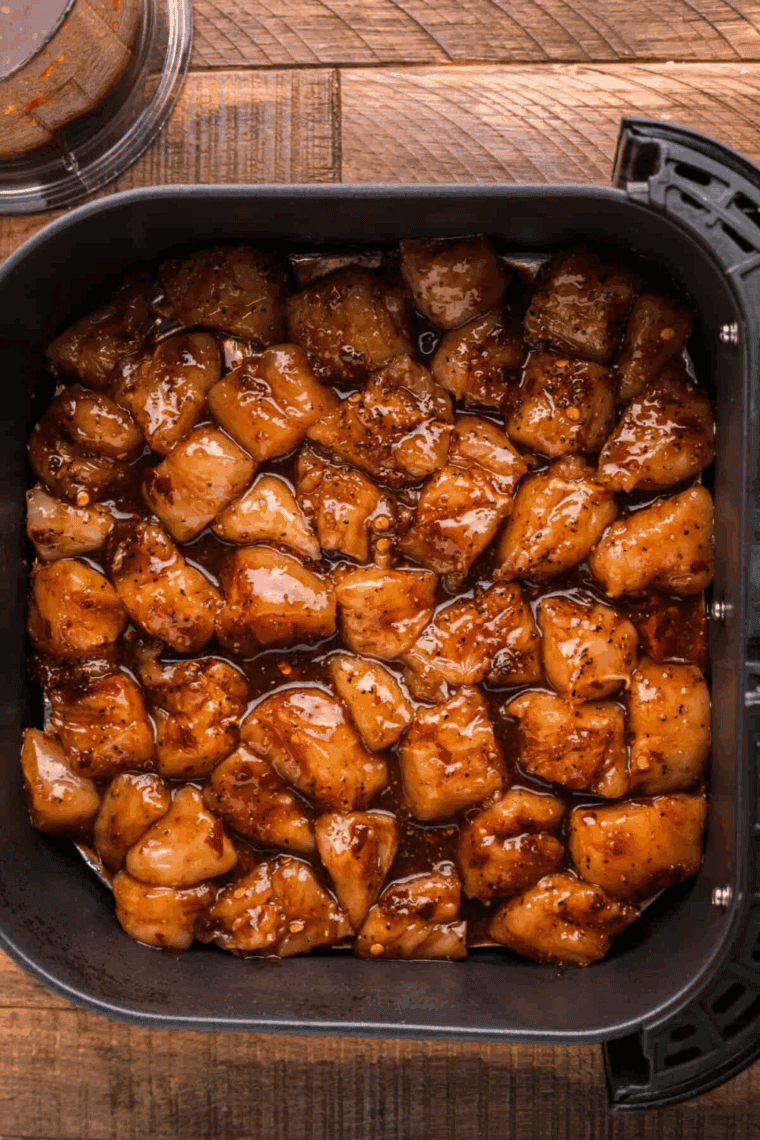 Chicken pieces arranged in a single layer in the air fryer basket, cooking at 370°F and flipped halfway for even crispiness.