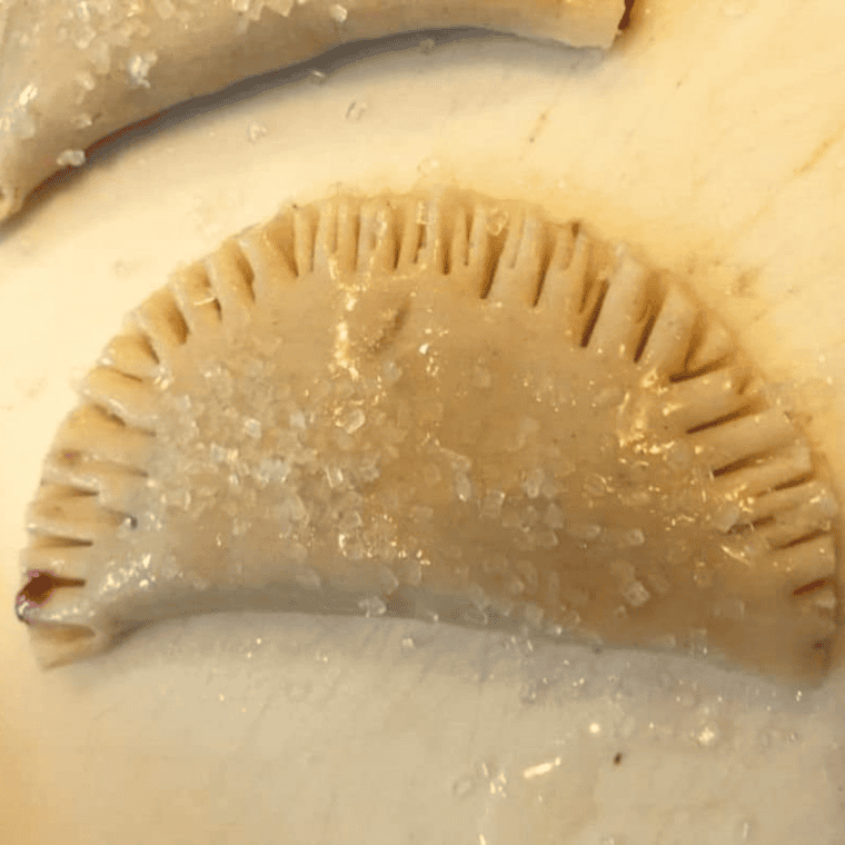 Placing top dough circles on filled hand pies and crimping edges with a fork