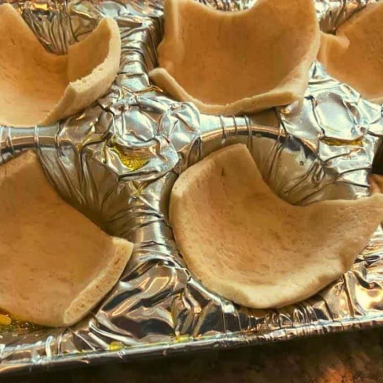 Spoonful of cherry pie filling added into crescent dough cups inside muffin tin