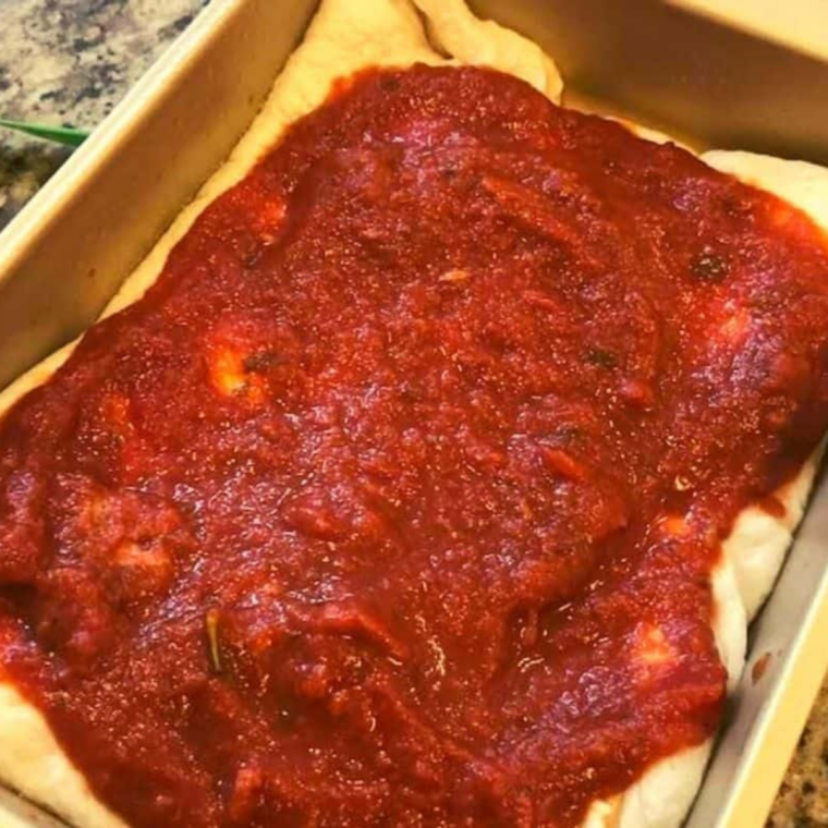 Chunky tomato sauce spooned over the mozzarella layer in an air fryer deep-dish pizza pan.