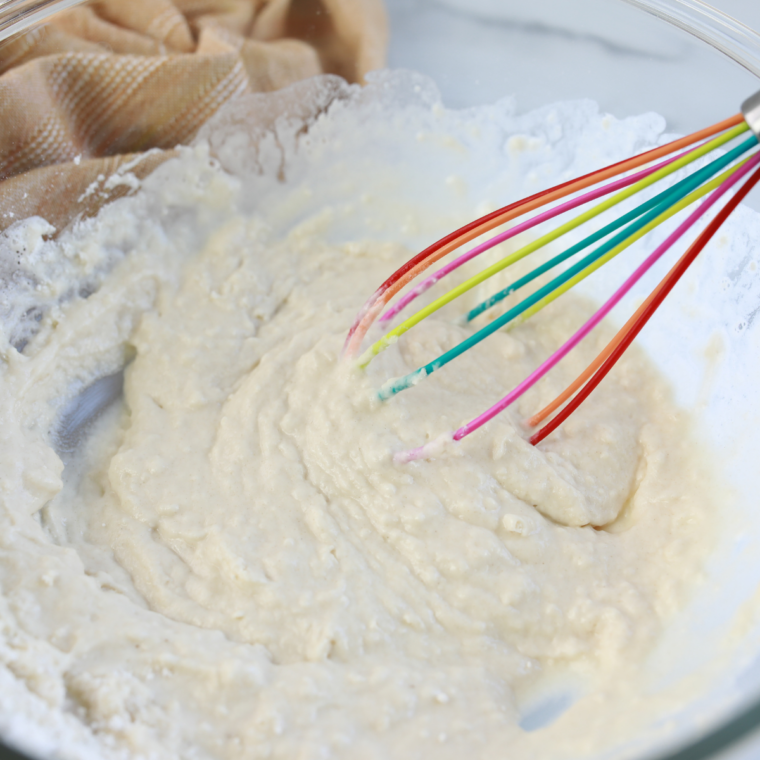 Whisking milk flour eggs butter salt and vanilla in bowl until smooth pancake batter forms
