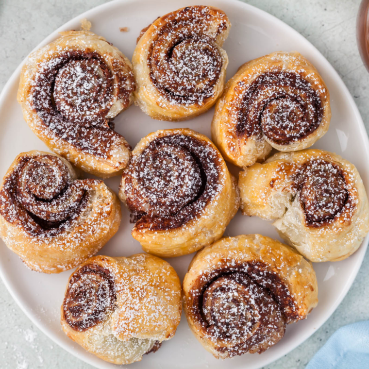 Nutella puff pastry bites in an air fryer basket after six minutes, puffed and deep golden brown