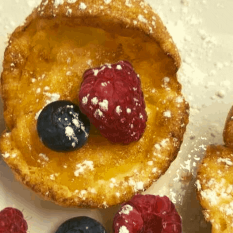 Golden mini Dutch pancakes cooked in air fryer fluffy and puffed with crisp edges and powdered sugar topping