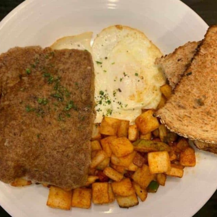 Air fryer scrapple slices drizzled with maple syrup on a breakfast plate