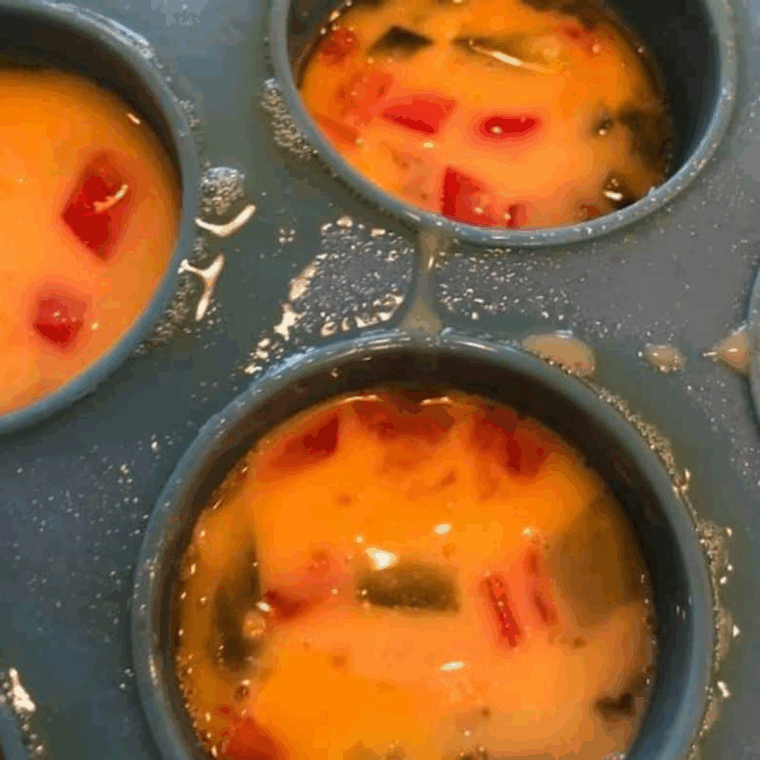 Silicone egg bite mold sprayed with olive oil, filled with egg mixture, cooking in the air fryer at 350°F until fully set.