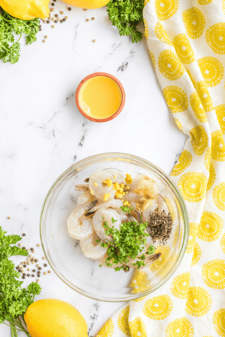 Small mixing bowl with melted butter, parsley, and garlic powder being stirred together.
