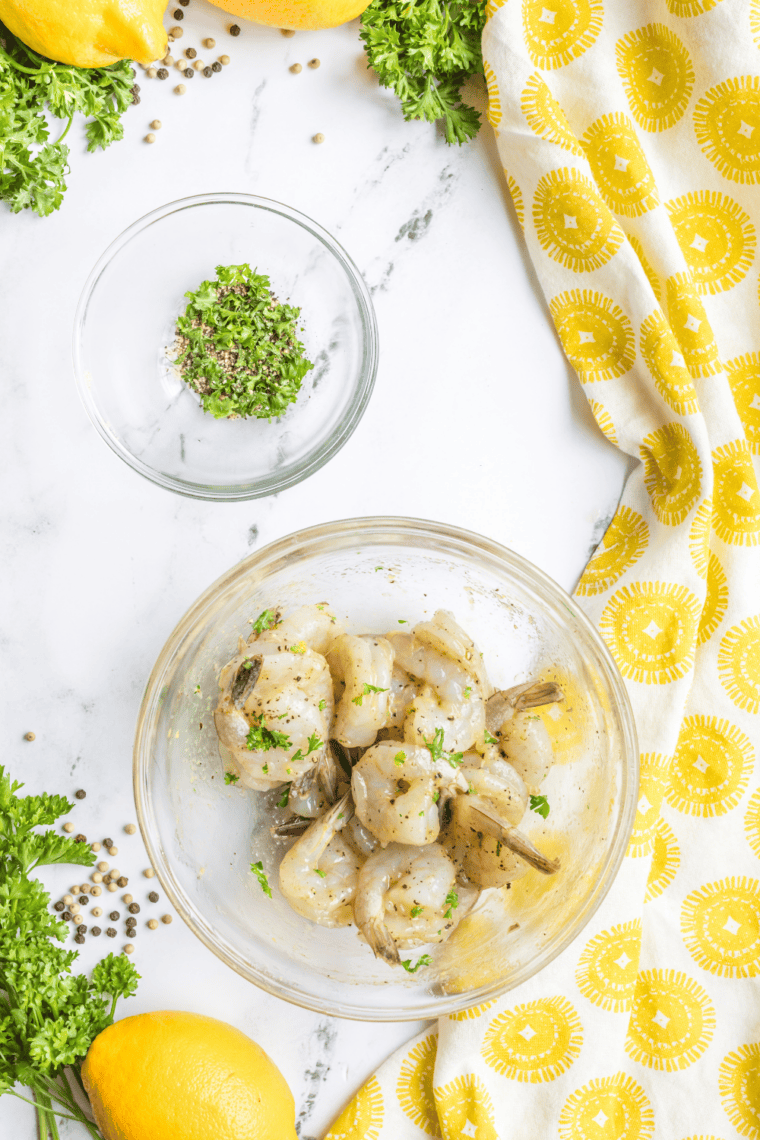 Colossal shrimp coated in garlic butter arranged in a lightly sprayed air fryer basket.