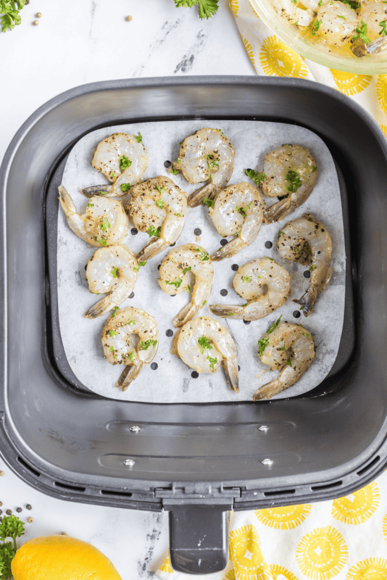 Colossal shrimp cooking in an air fryer, being brushed with fresh lemon juice.