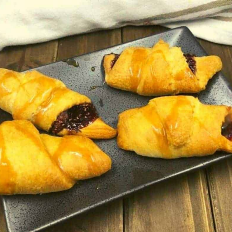 Golden brown raspberry crescent rolls cooking in the air fryer basket until puffed and crisp.