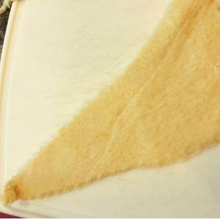 Crescent roll dough unrolled and separated into triangle pieces on a clean kitchen surface.