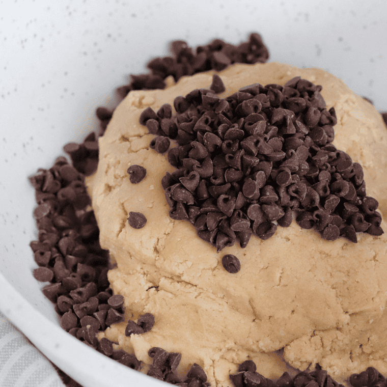 Greasing an air fryer pan and pressing cookie dough evenly inside.