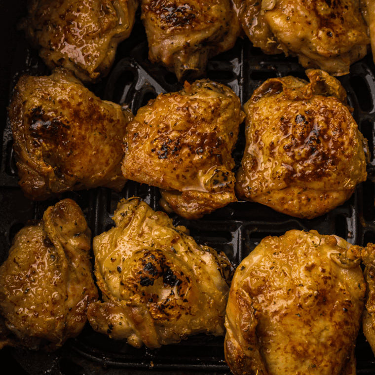 Cooked Chicken thighs in the air fryer basket.
